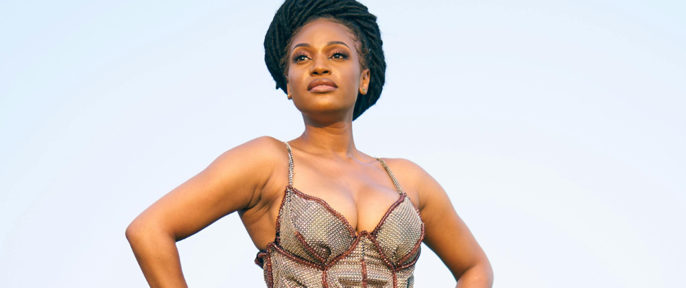 Confident black woman with stylish dress standing outside.